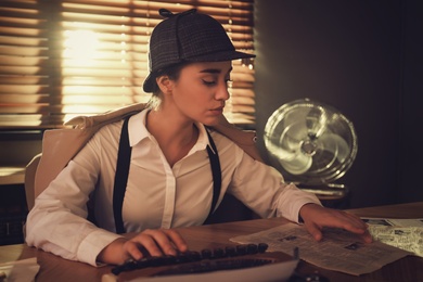 Photo of Old fashioned detective using typewriter at table in office