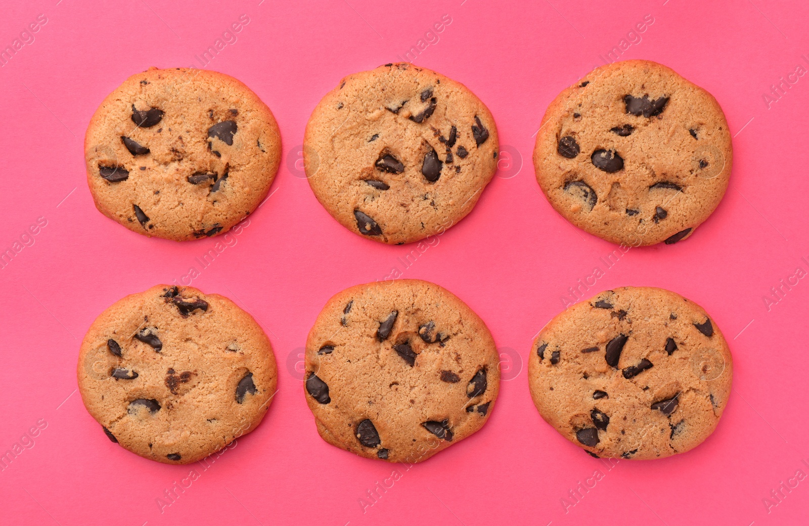 Photo of Many delicious chocolate chip cookies on pink background, flat lay