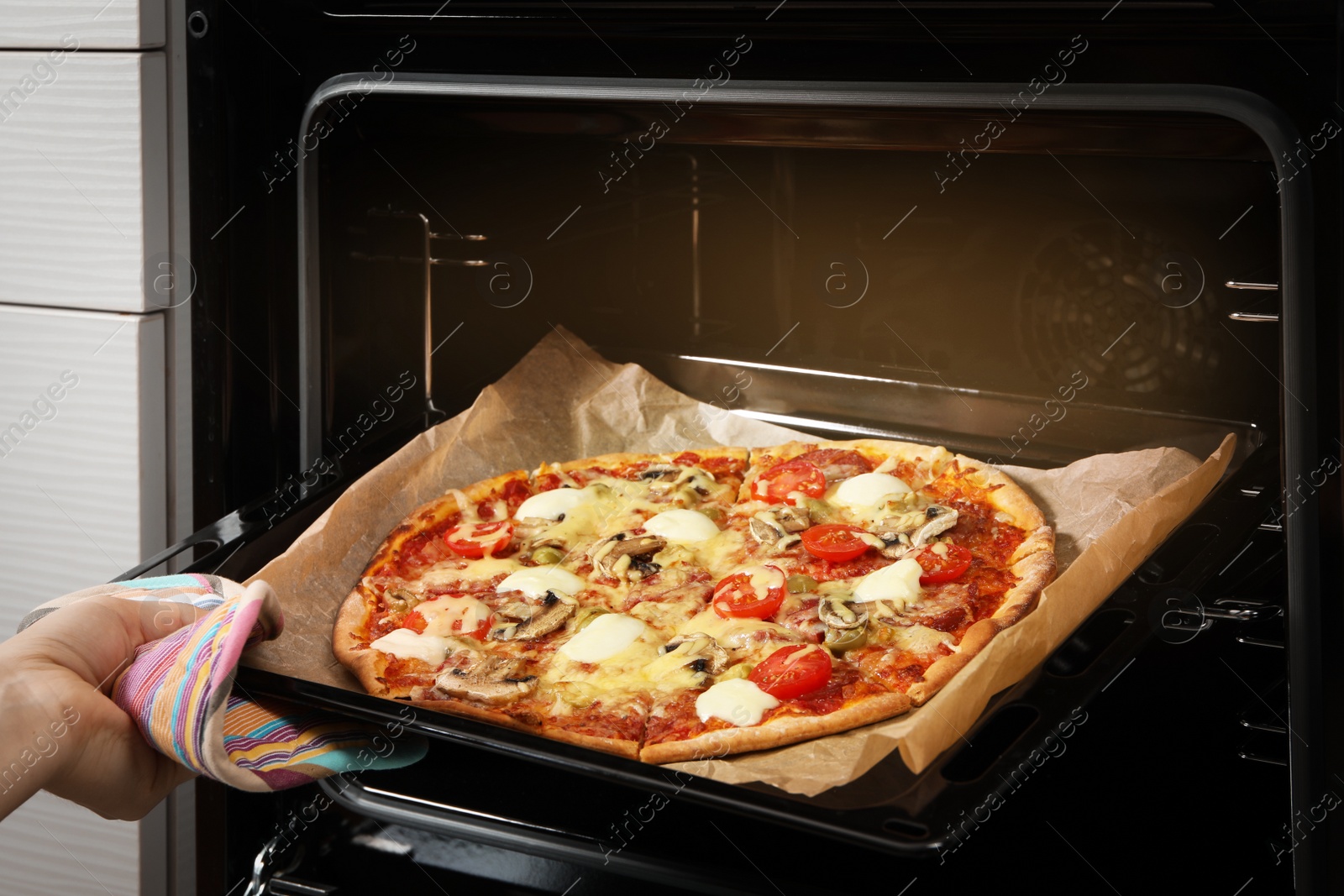 Photo of Woman taking tasty homemade pizza out of oven, closeup