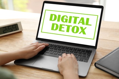 Woman using laptop with text Digital Detox at table, closeup