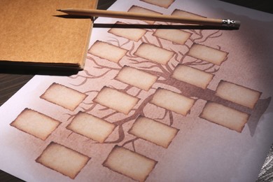 Photo of Blank family tree, notebook and pencil on table, closeup