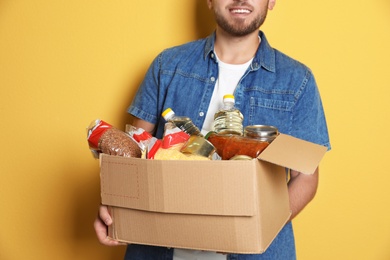 Young man holding box with donations on color background