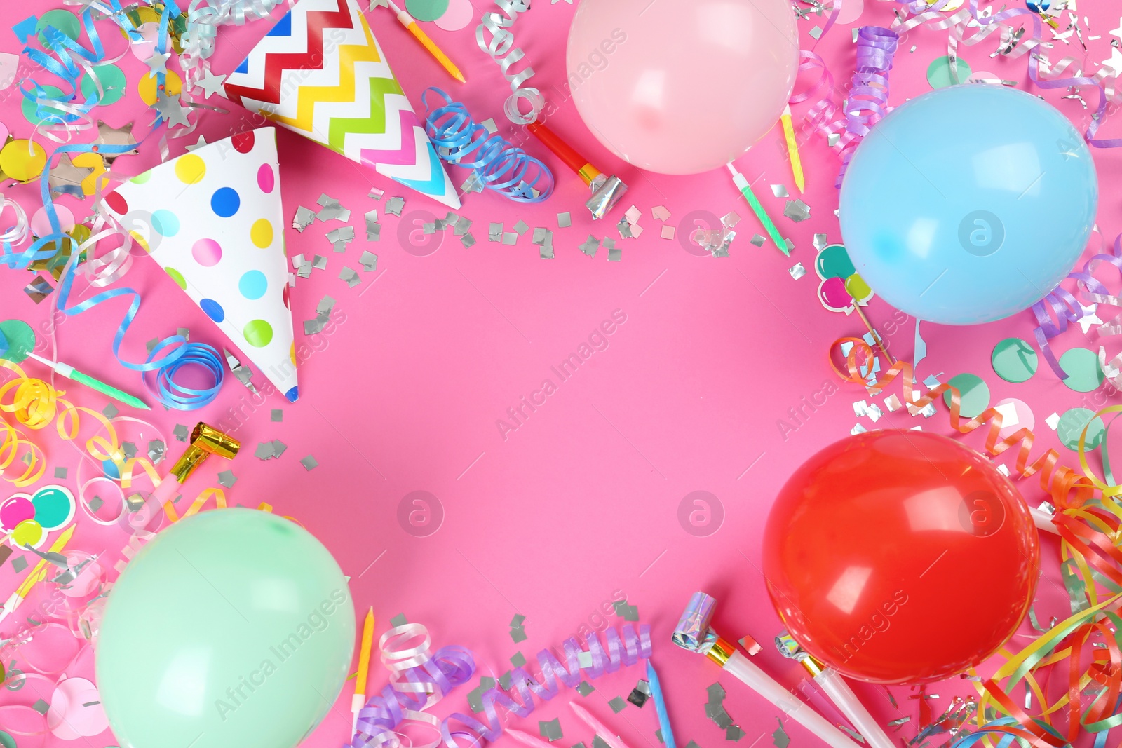 Photo of Frame of colorful serpentine streamers and other party accessories on pink background, flat lay. Space for text