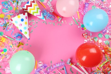 Frame of colorful serpentine streamers and other party accessories on pink background, flat lay. Space for text