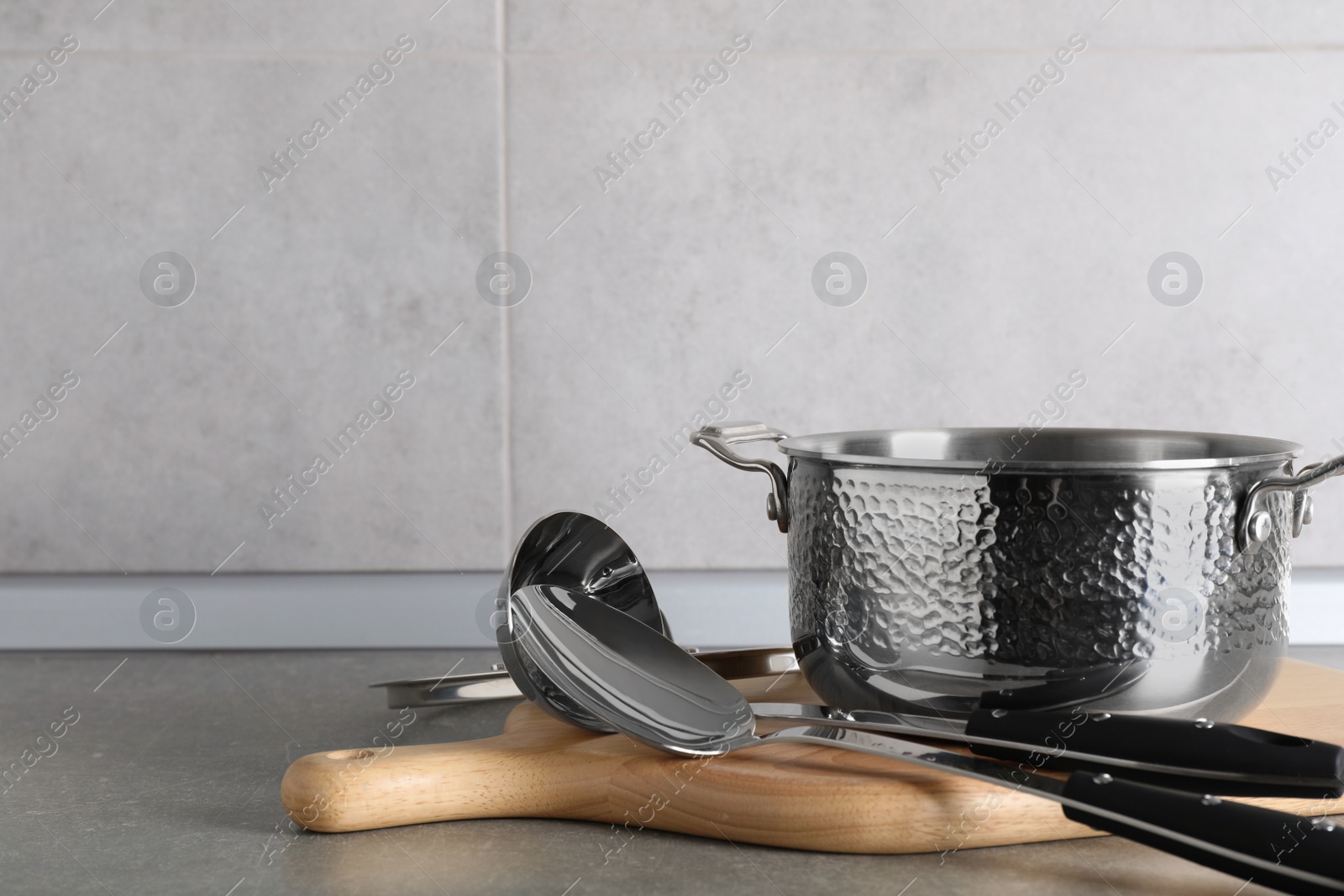 Photo of Set of different cooking utensils on grey countertop in kitchen. Space for text