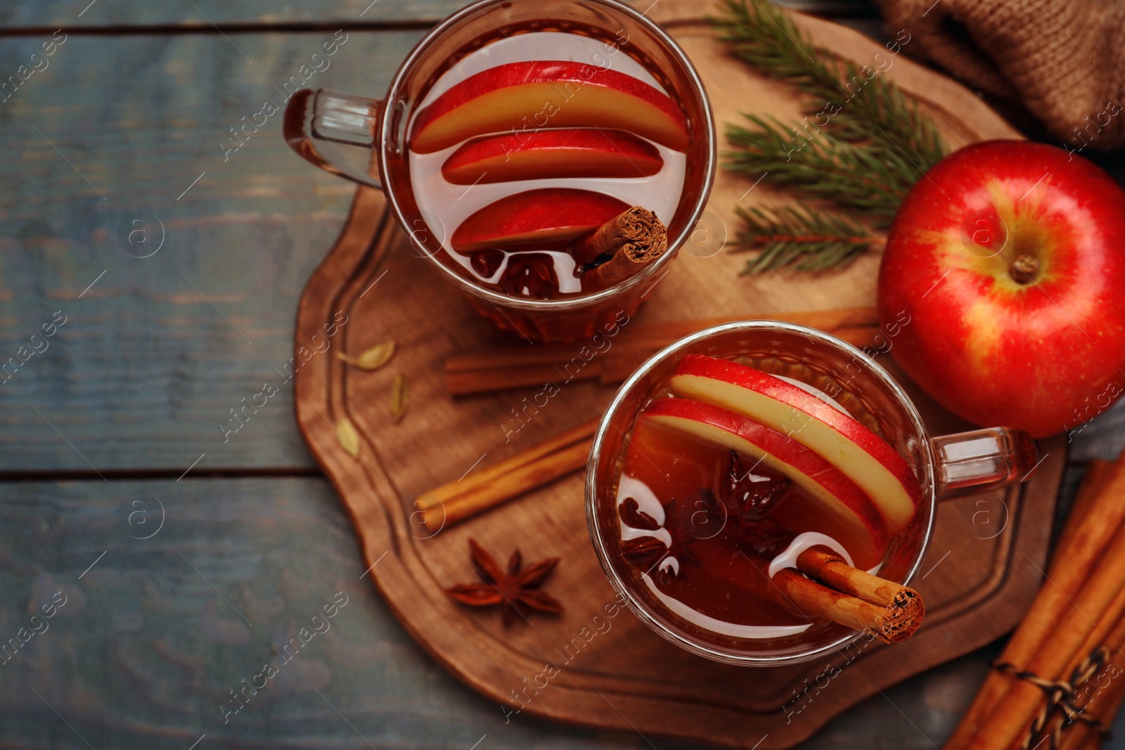 Photo of Aromatic hot mulled cider on light blue wooden table, flat lay