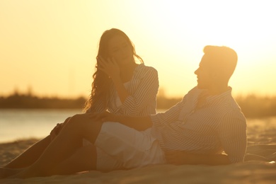 Happy young couple resting together on beach at sunset