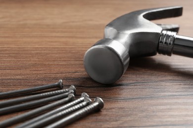 Photo of Hammer and metal nails on wooden table, closeup