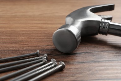 Hammer and metal nails on wooden table, closeup