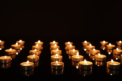 Burning candles on mirror surface in darkness