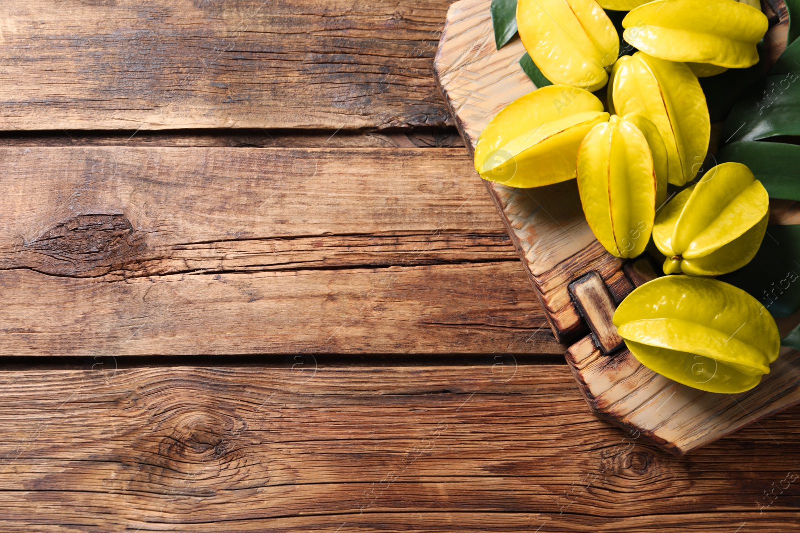 Photo of Delicious carambola fruits on wooden table, top view. Space for text