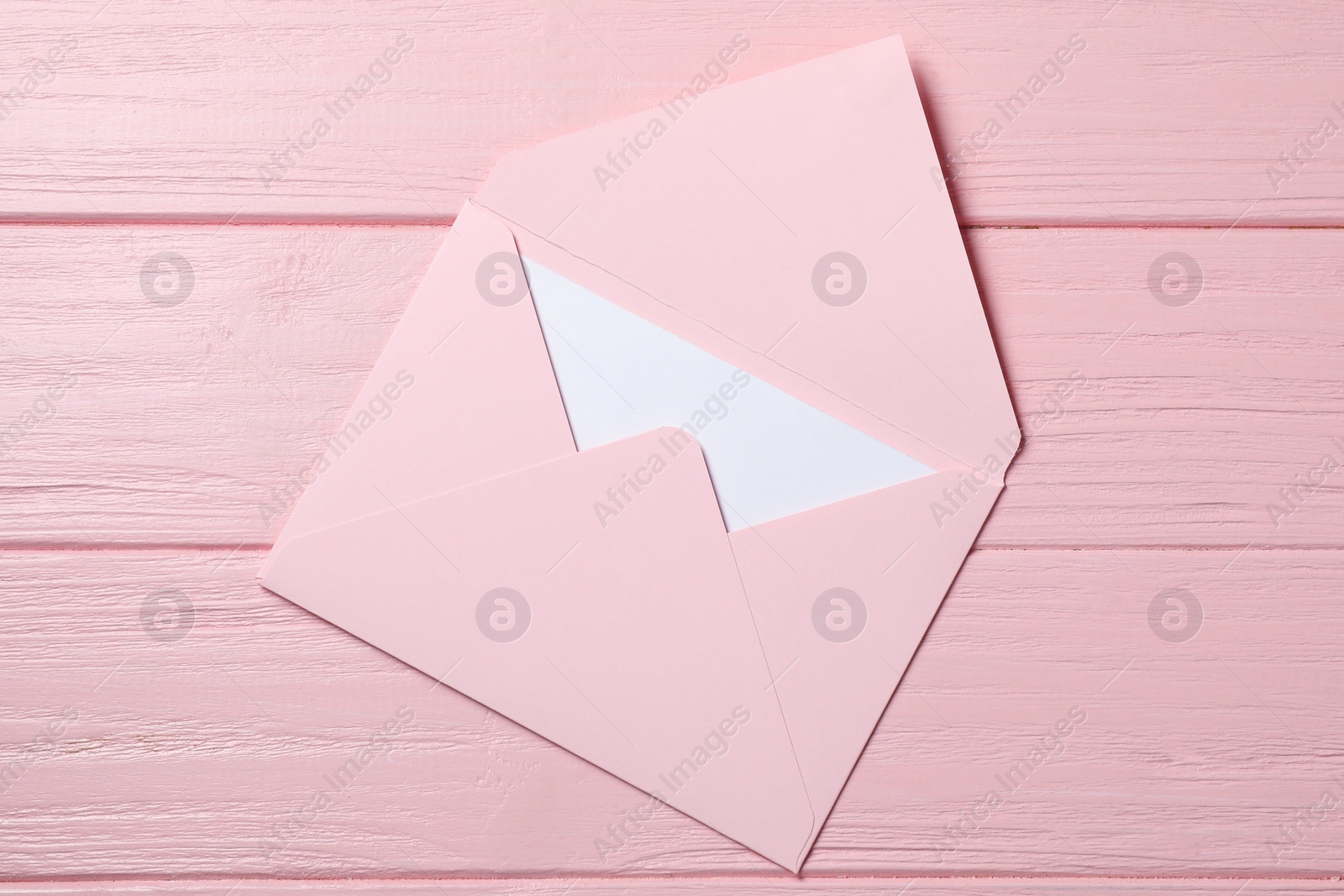 Photo of Letter envelope with card on pink wooden table, top view