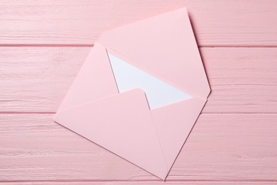 Photo of Letter envelope with card on pink wooden table, top view