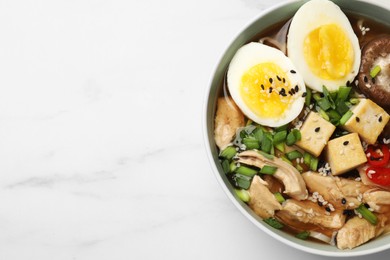 Bowl of delicious ramen on white marble table, top view with space for text. Noodle soup