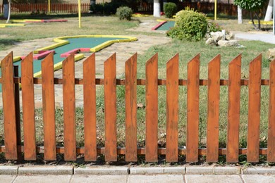 Photo of Wooden fence near mini golf court on sunny day outdoors