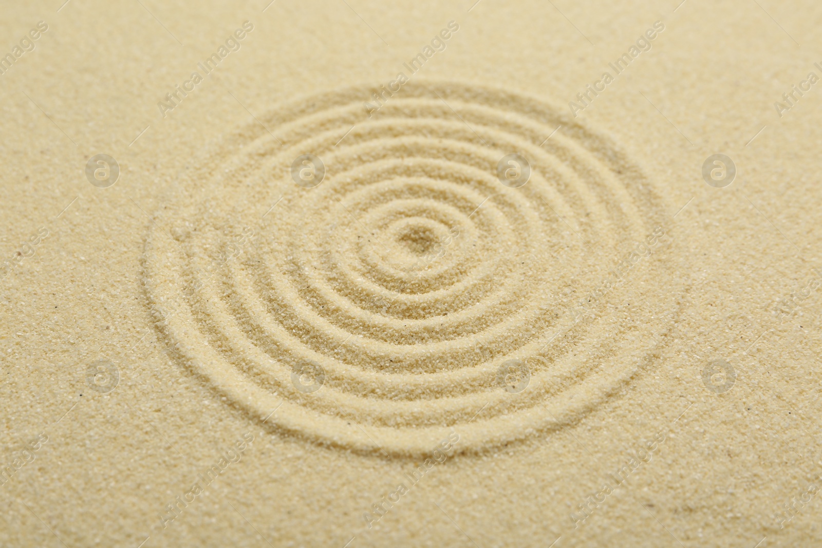 Photo of Zen rock garden. Circle pattern on beige sand