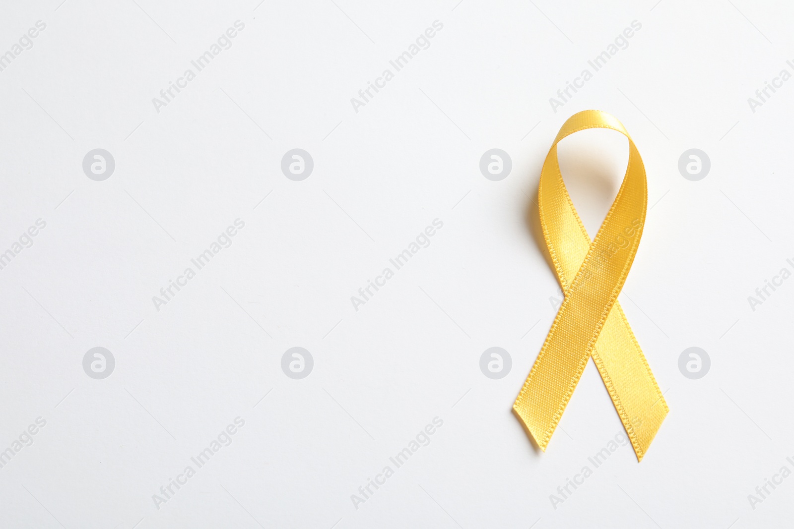 Photo of Yellow ribbon on white background, top view. Cancer awareness