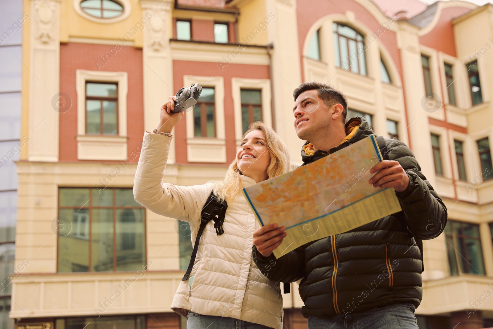 Photo of Couple of tourists with map and camera on city street