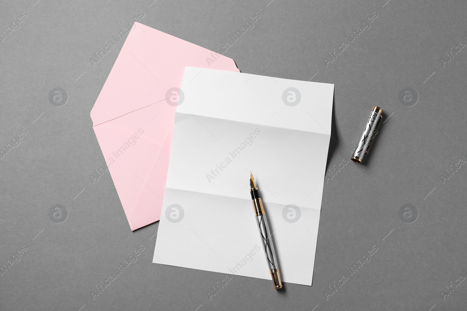 Photo of Blank sheet of paper, letter envelope and pen on grey background, top view