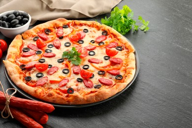 Tasty pizza with dry smoked sausages, olives, tomato, pepper and parsley on grey table