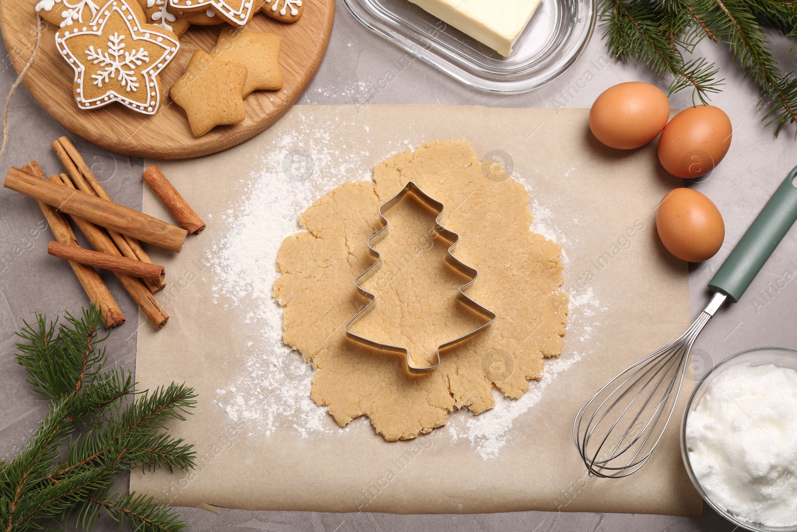 Photo of Making Christmas cookies. Flat lay composition with ingredients and raw dough on grey table