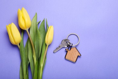 Beautiful spring flowers and key with trinket in shape of house on violet background, flat lay