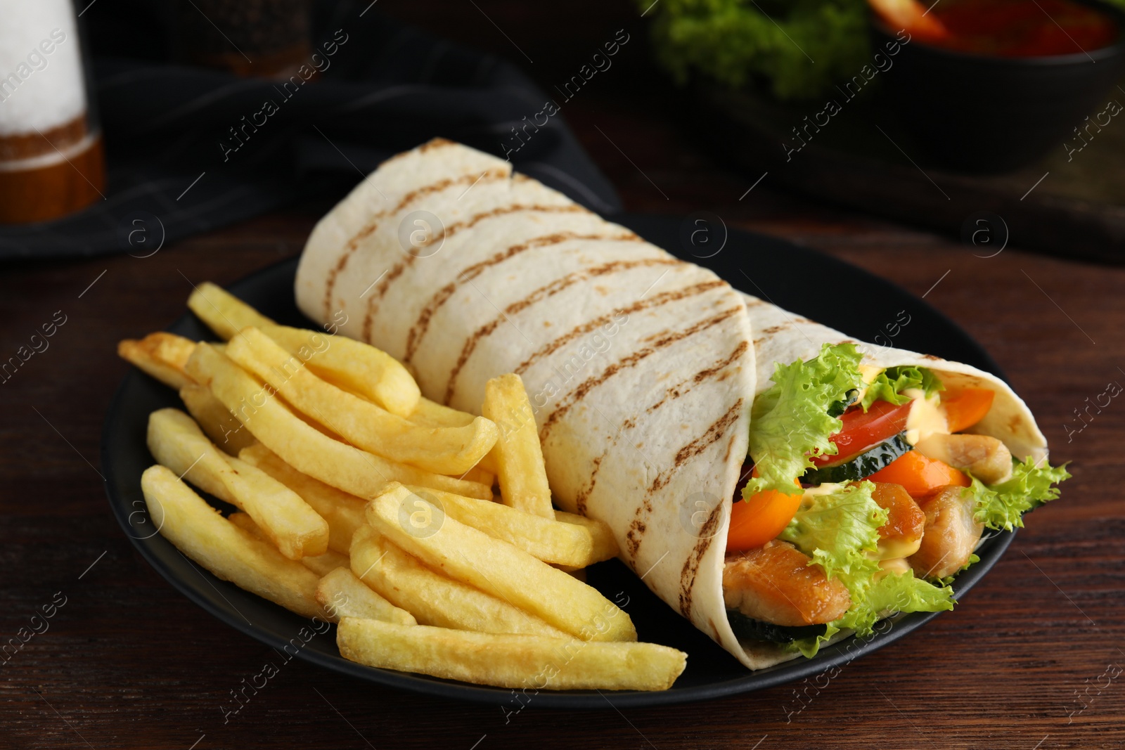 Photo of Delicious chicken shawarma and French fries on wooden table, closeup