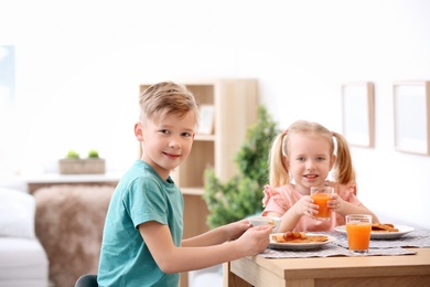 Photo of Adorable little children eating tasty toasted bread with jam at table