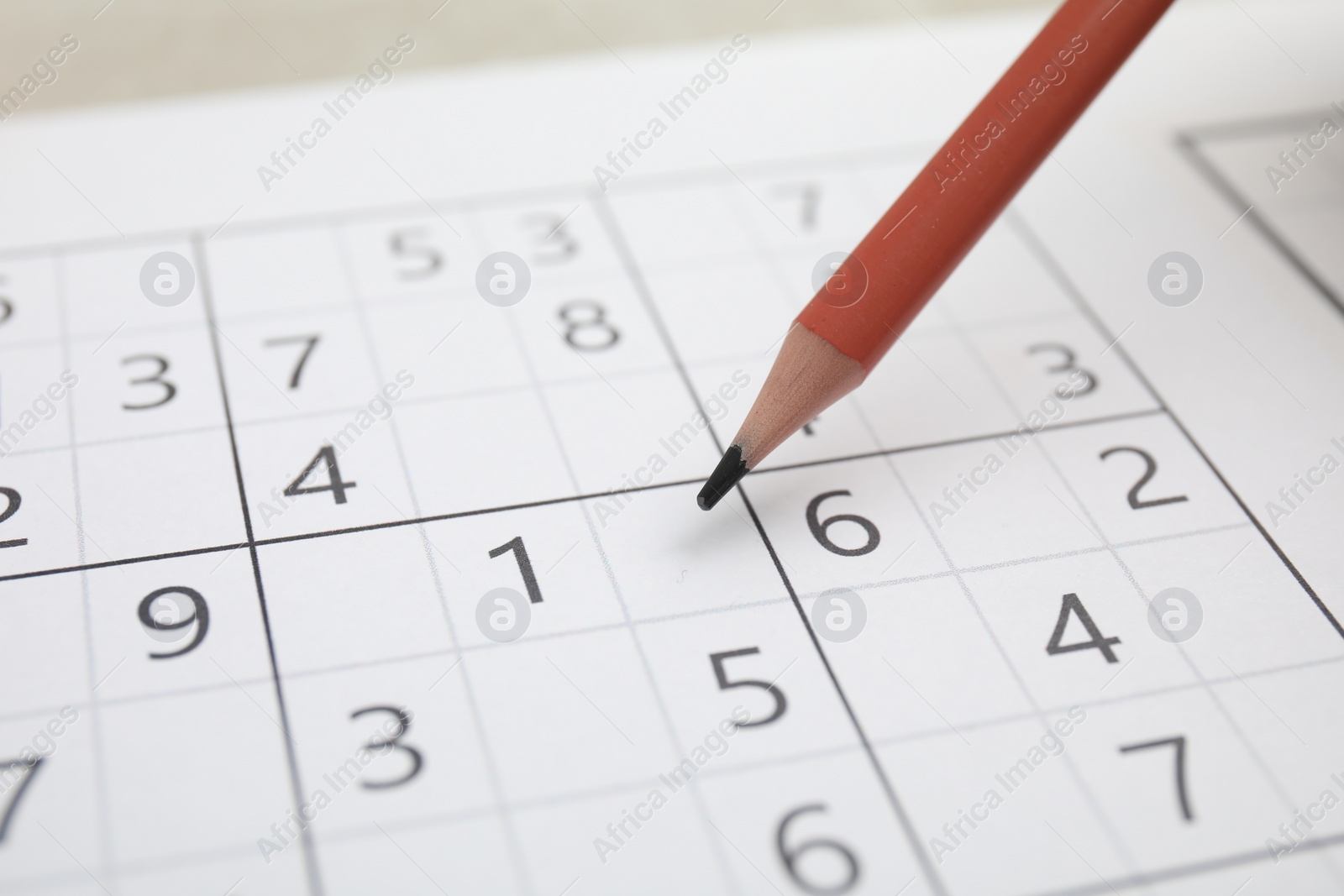 Photo of Sudoku puzzle grid and pencil, closeup view