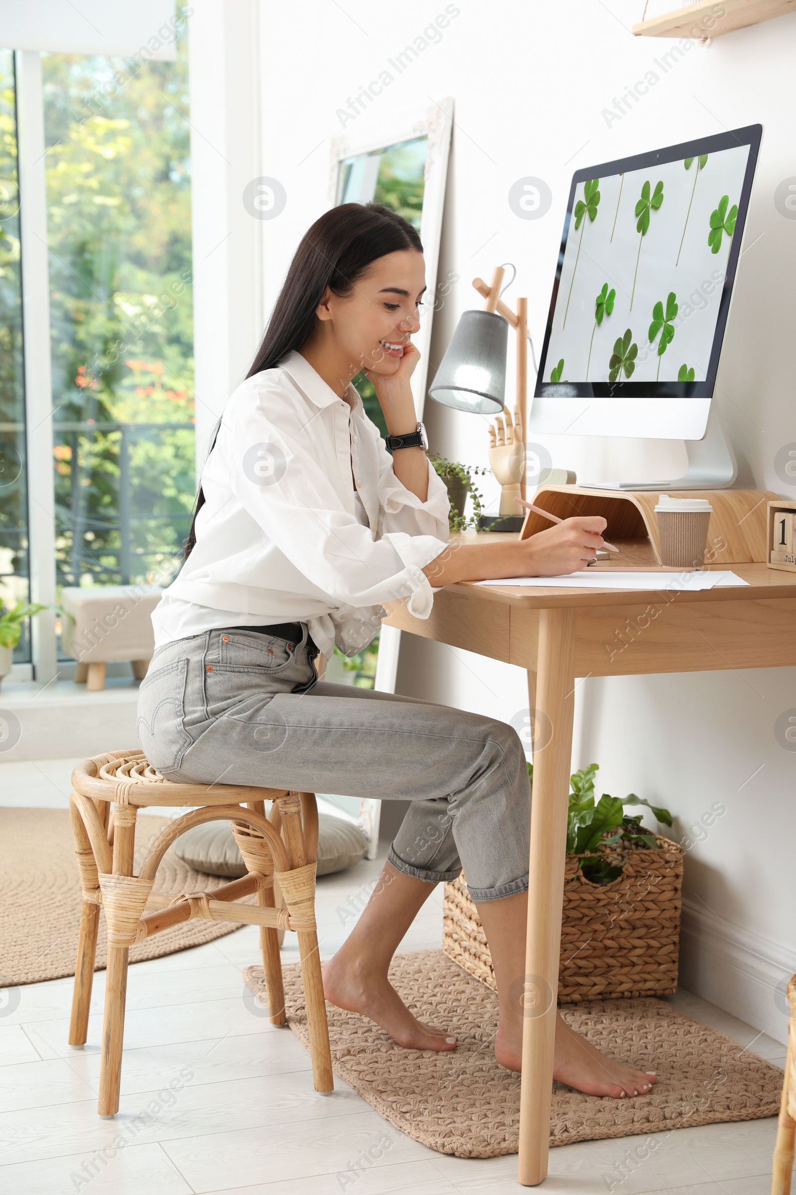 Photo of Young woman working at table in light room. Home office