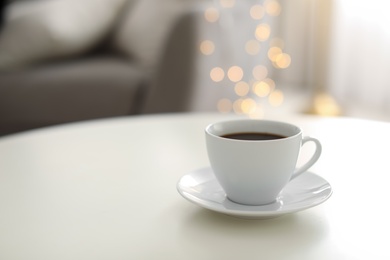 Photo of Cup of coffee on table indoors, space for text. Bokeh effect