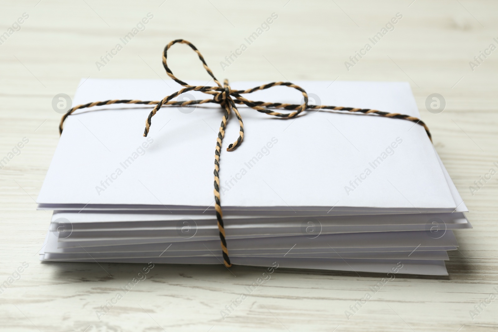 Photo of Stack of letters tied with string on white wooden table, closeup