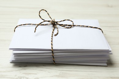 Photo of Stack of letters tied with string on white wooden table, closeup