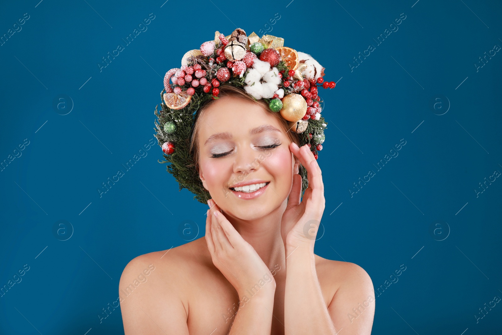 Photo of Beautiful young woman wearing Christmas wreath on blue background