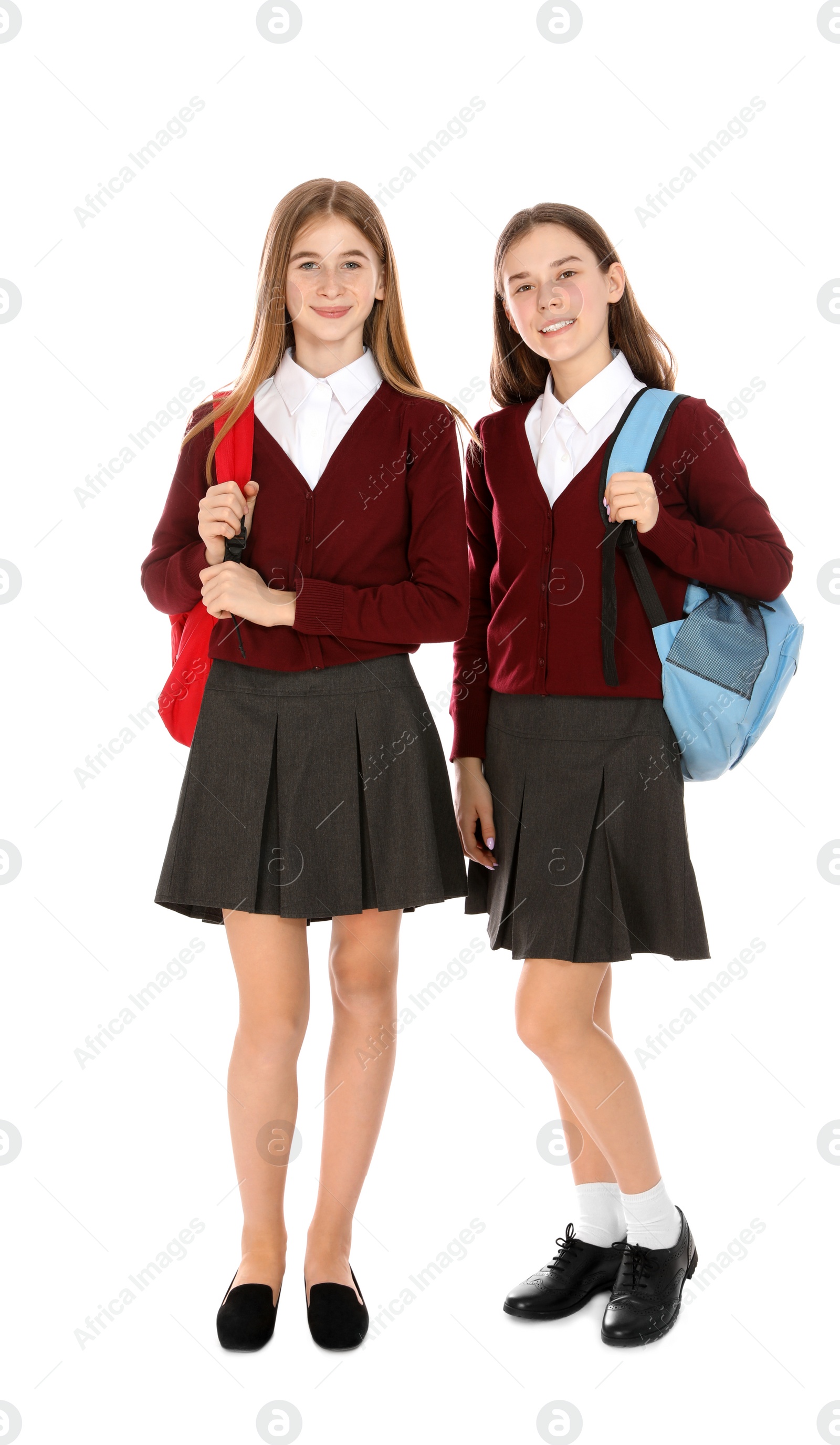 Photo of Full length portrait of teenage girls in school uniform with backpacks on white background