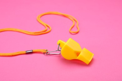 Photo of One yellow whistle with cord on pink background