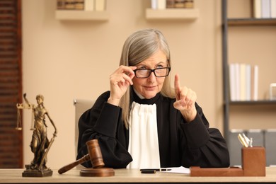 Photo of Judge in court dress working at table indoors