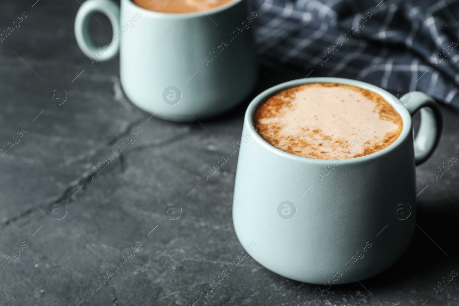 Photo of Cups of delicious hot cocoa on grey table. Space for text