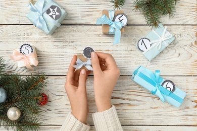 Woman making advent calendar at white wooden table, top view