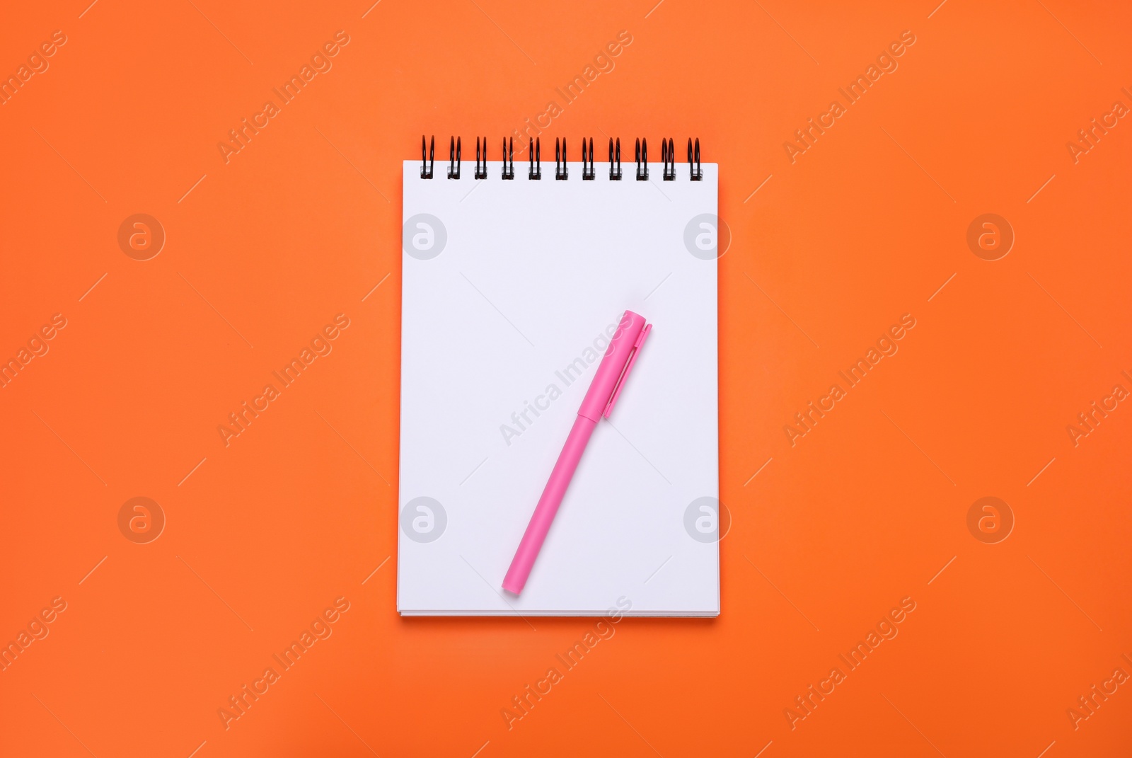 Photo of Blank office notebook and pen on orange background, top view