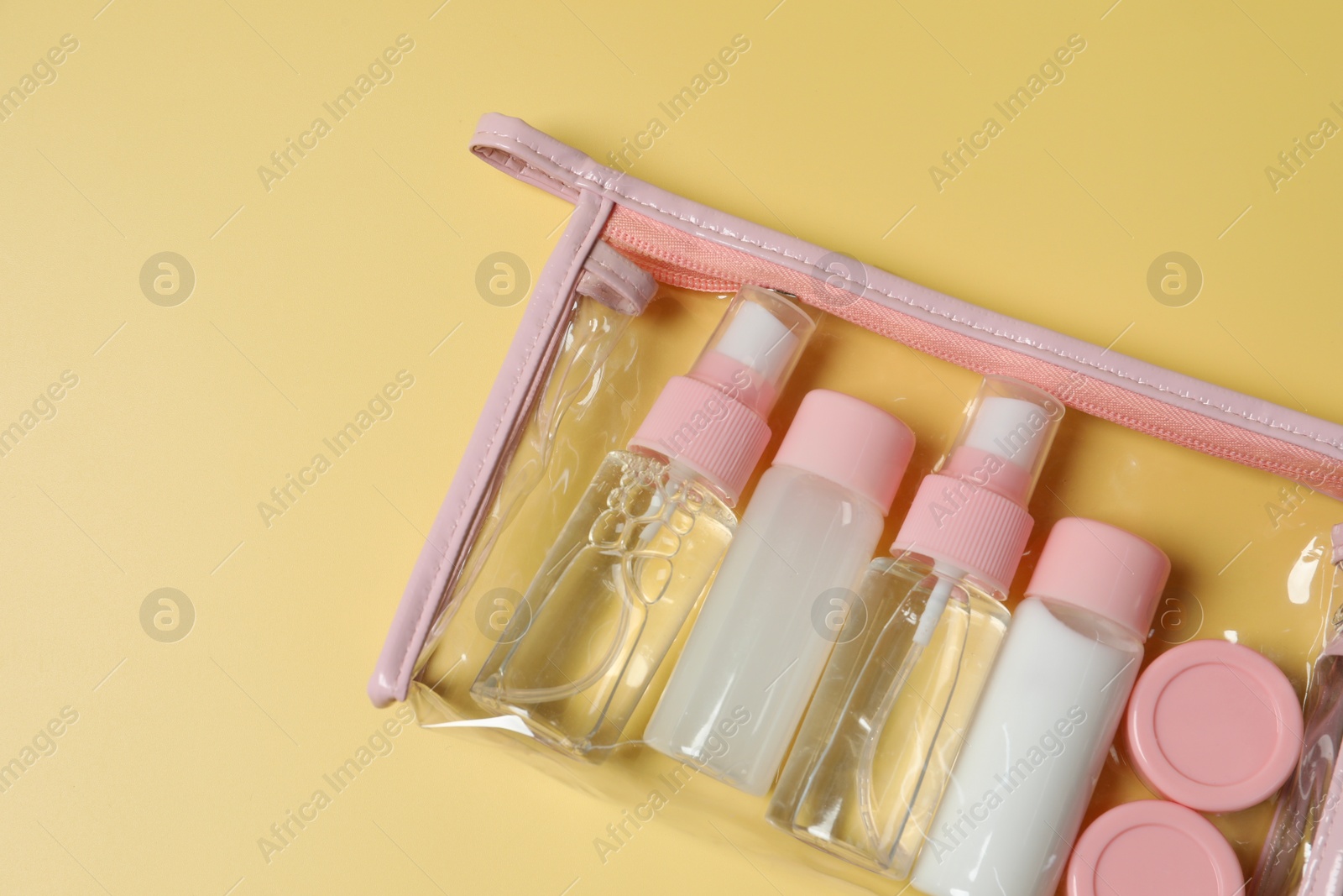 Photo of Cosmetic travel kit in plastic bag on yellow background, top view. Space for text