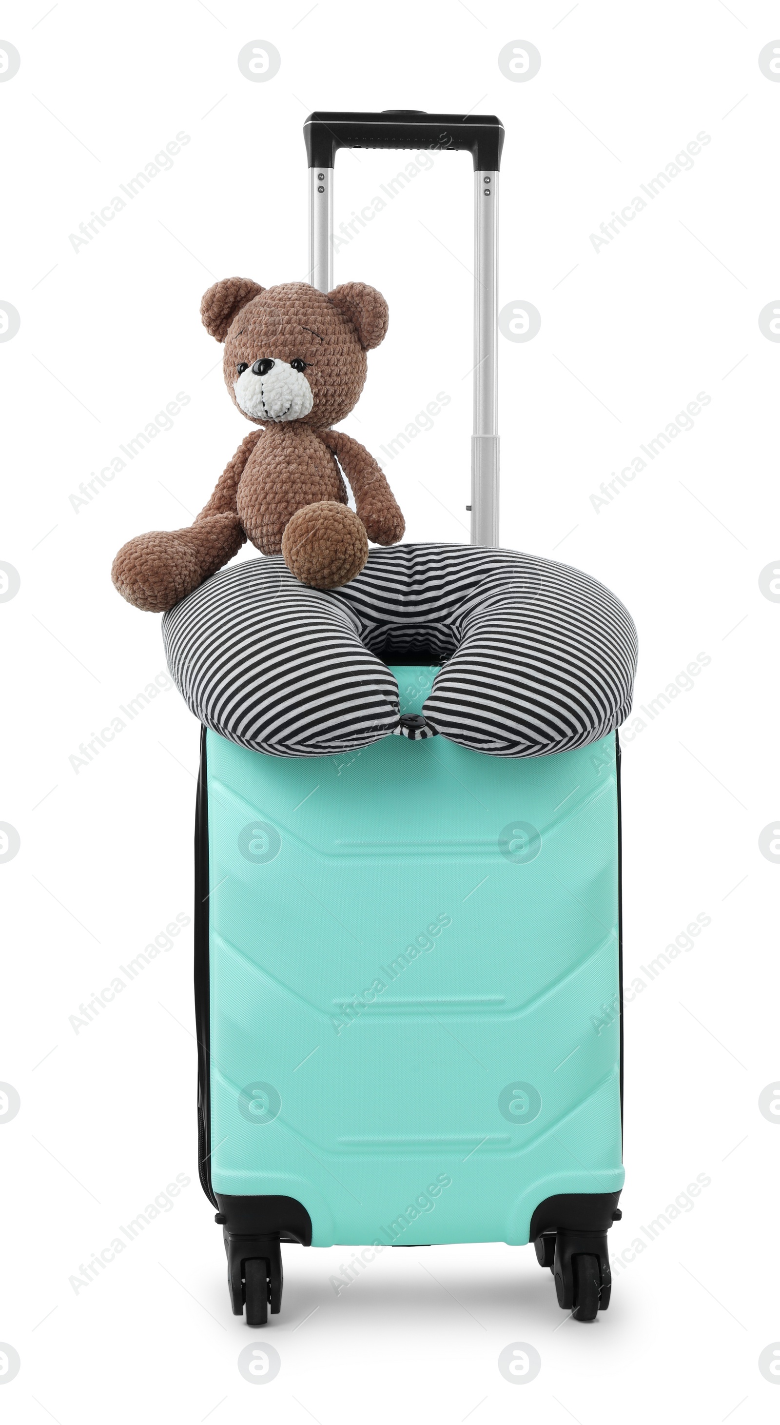 Photo of Soft travel pillow and toy bear on turquoise suitcase isolated on white