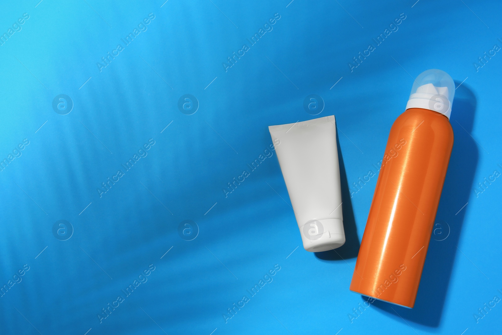 Photo of Sunscreens on light blue background, flat lay and space for text. Sun protection care