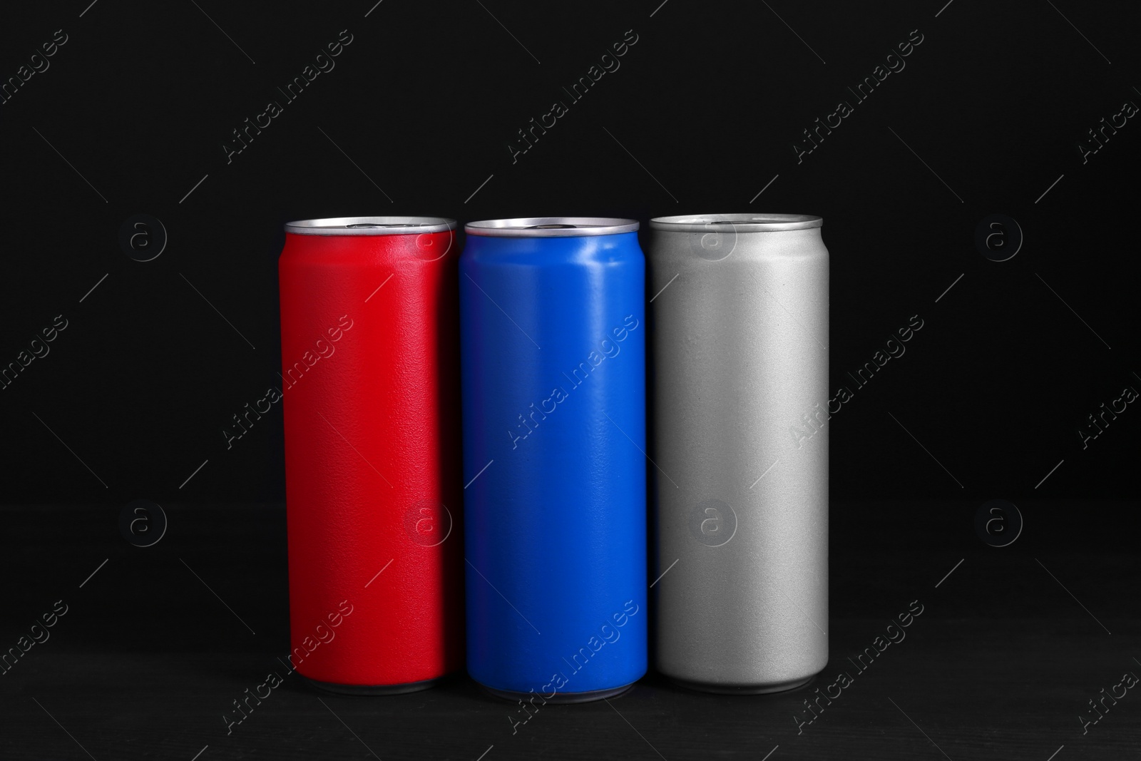 Photo of Energy drinks in colorful cans on black wooden table