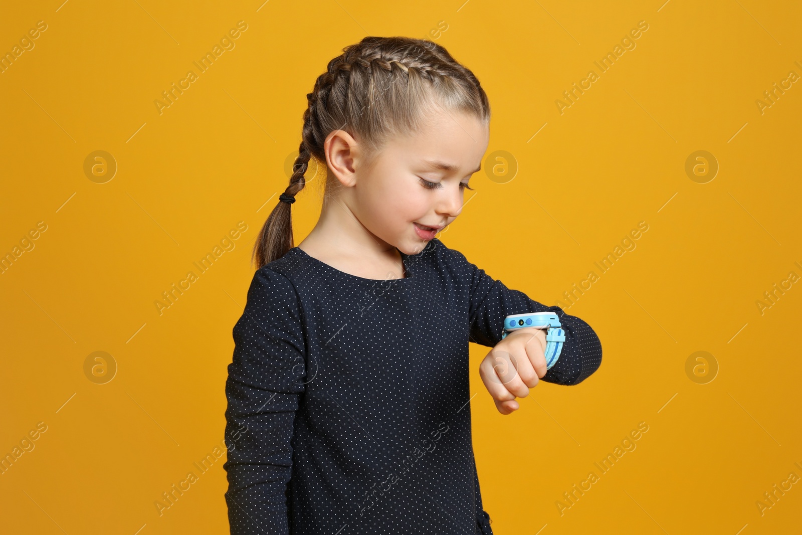 Photo of Little girl with smart watch on yellow background