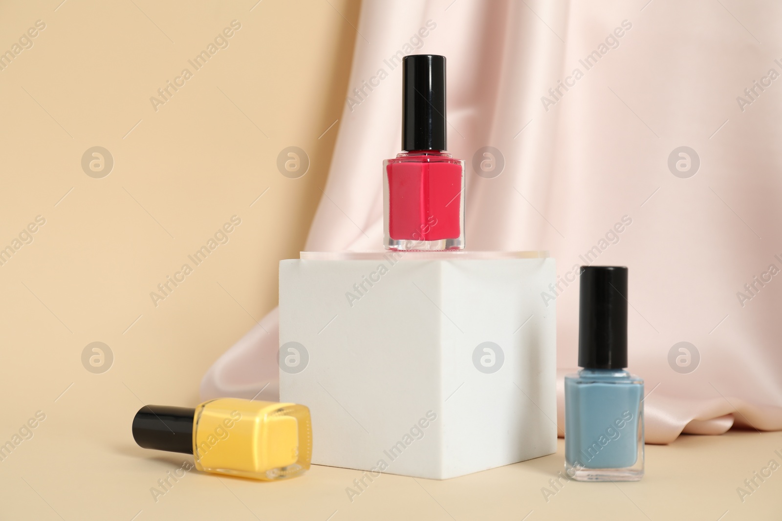 Photo of Stylish presentation of nail polishes on beige background