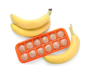 Photo of Banana puree in ice cube tray and fresh banana fruits isolated on white, top view
