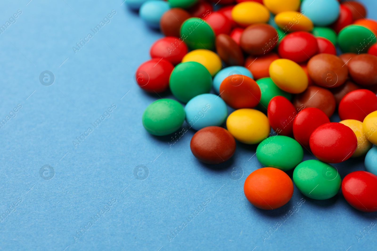 Photo of Tasty colorful candies on blue background, closeup. Space for text