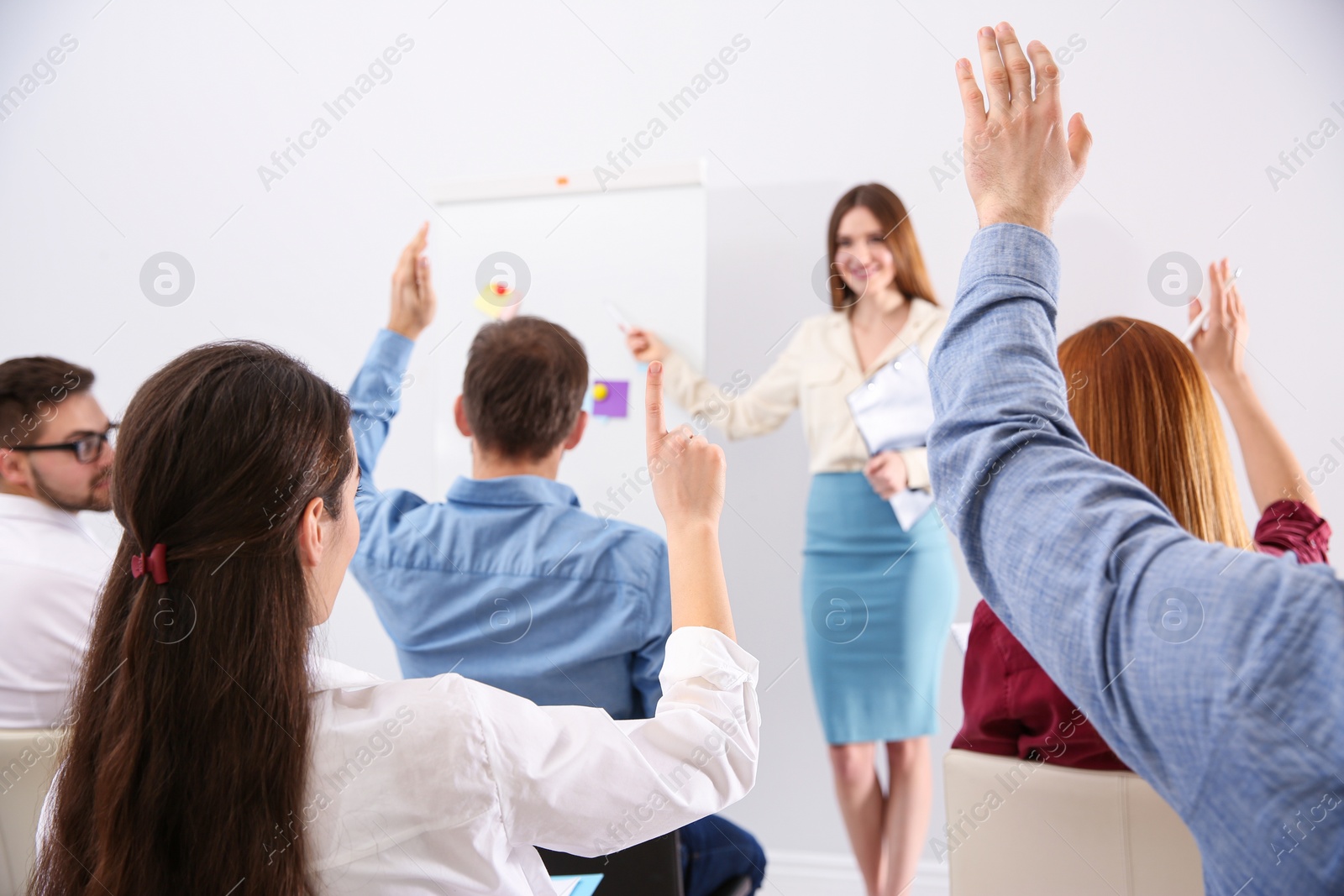 Photo of People raising hands to ask questions at business training indoors