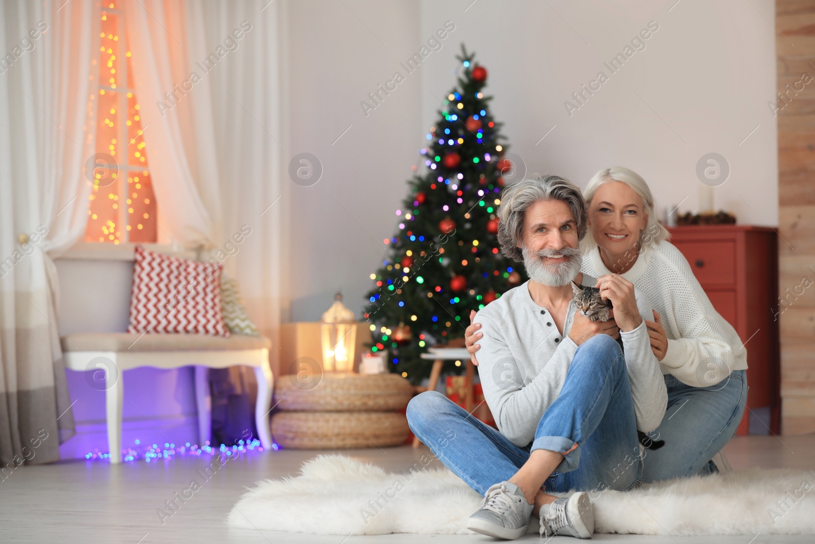 Photo of Happy couple with cute cat celebrating Christmas at home